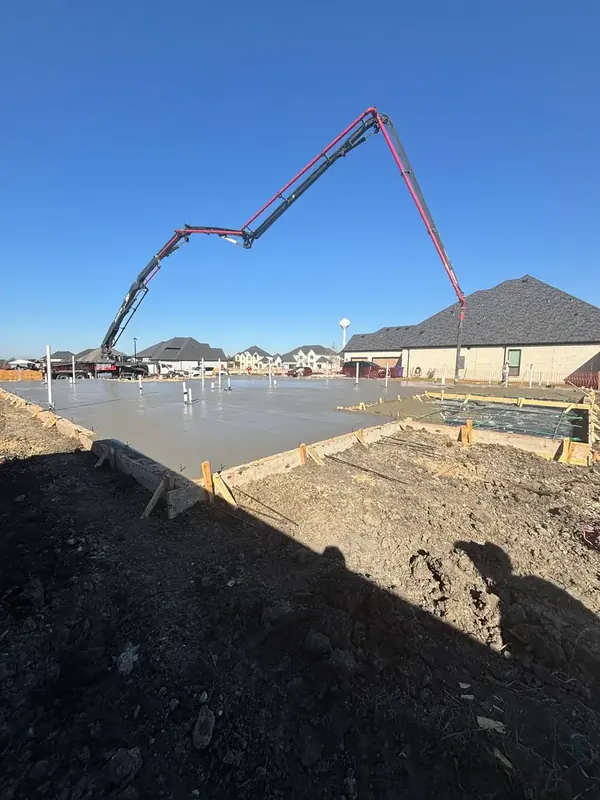 Pump truck boom extended over a residential foundation pour in a new neighborhood